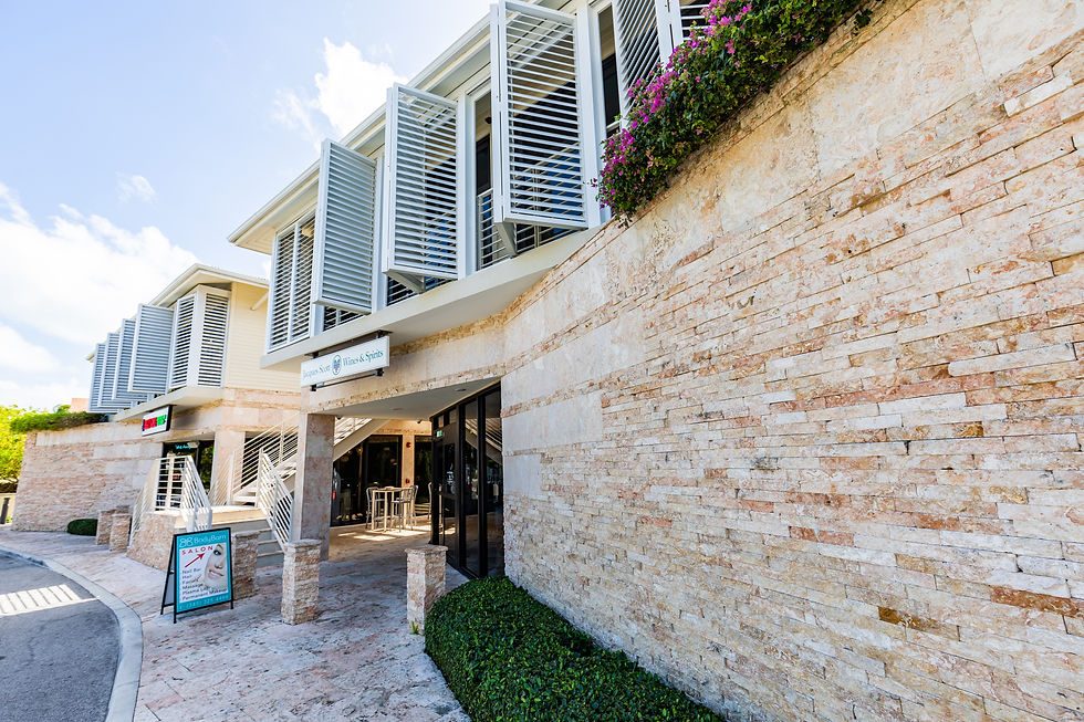 The stone-clad frontage and shaded entrance of Jacques Scott Plaza in West Bay