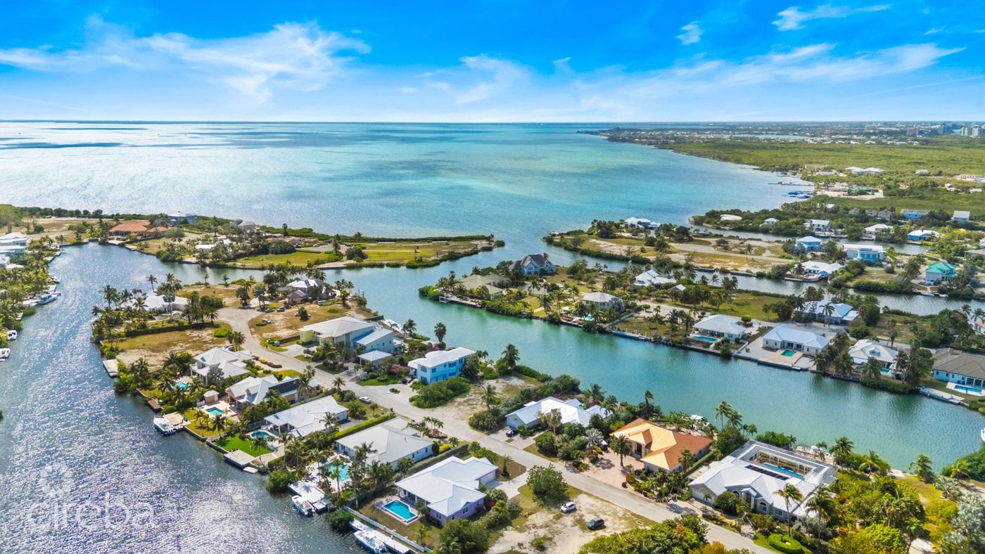 Aerial view of The Shores, a canal-front community in West Bay, with homes and moorings lining the waterway out to the North Sound